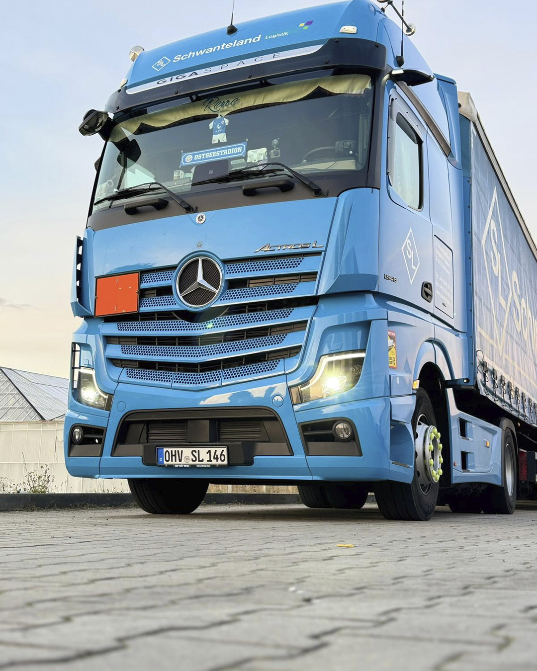 Blauer Mercedes Actros-Lkw mit Aufschrift 'Schwanteland Logistik' auf der Front, geparkt auf gepflastertem Boden.