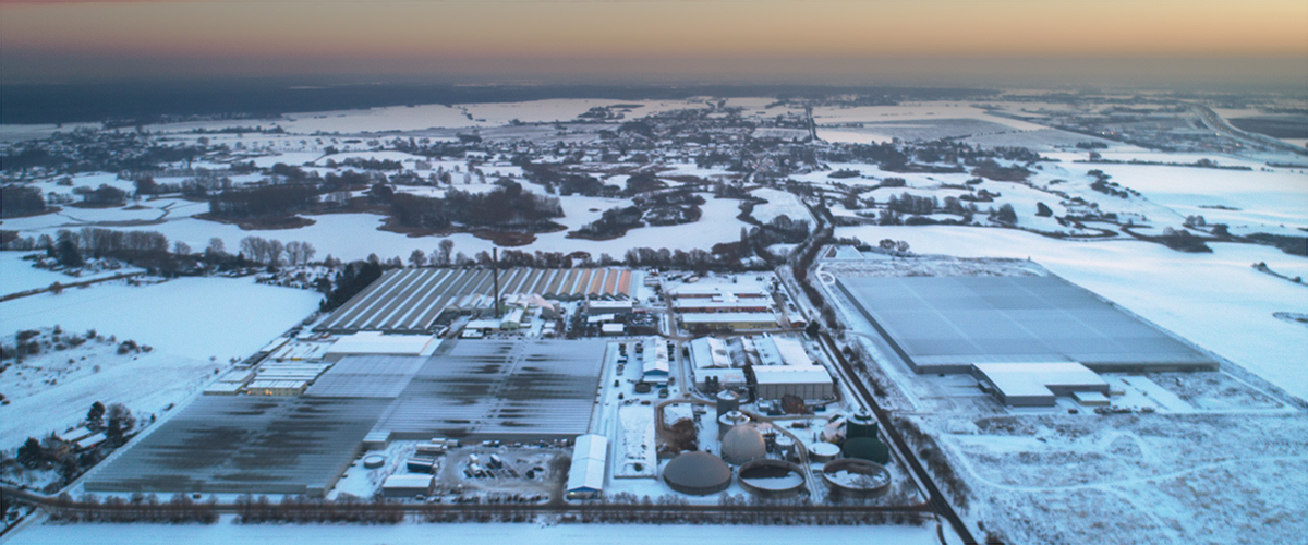 Luftaufnahme des schneebedeckten Firmenstandorts der Schwanteland Gruppe mit mehreren großen Hallen und Gebäuden in einer ländlichen Winterlandschaft